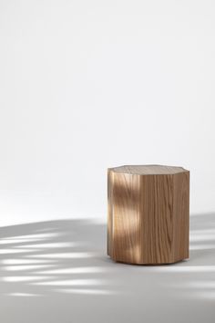 a small wooden box sitting on top of a white floor next to a shadow cast wall