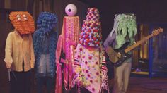 four people are dressed up in colorful wigs and playing the guitar while standing next to each other