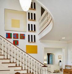 a staircase in the middle of a living room with paintings on the wall behind it