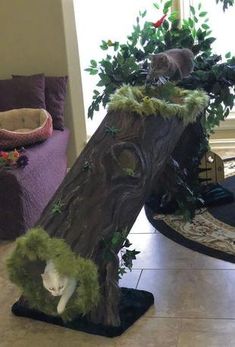 two cats are sitting on top of a tree stump in the middle of a living room