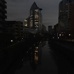 a river running through a city at night with tall buildings in the backgroud