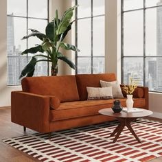 a living room with large windows and a couch in front of a table on top of a rug