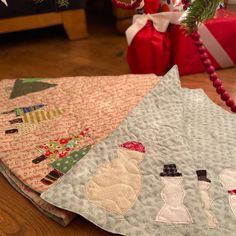 three quilts are sitting on the floor next to a christmas tree