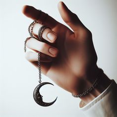 a woman's hand holding onto a chain with two rings hanging from the middle