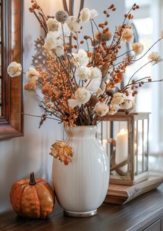 a white vase filled with flowers sitting on top of a wooden table next to a mirror