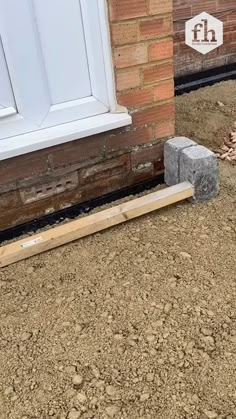 a cement block laying on the ground next to a brick wall with a door and window