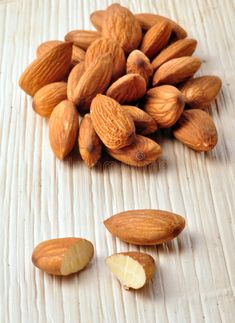 almonds on a wooden table with one half peeled and the other half unpeeled