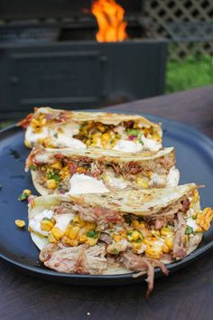 three quesadillas stacked on top of each other on a plate in front of an open fire pit