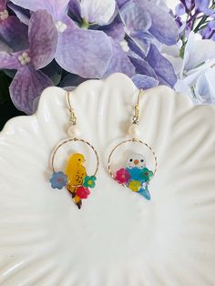 These charming handmade earrings feature  two different kinds of adorable parrots adorned with glistening fresh water pearls delicately dangled as drop earrings. Handmade of shrink plastic, these delicate bird pieces could be a perfect gift for bird enthusiasts and those who appreciate unique, artisanal jewelry.  These earrings capture the whimsical beauty of nature and make a delightful addition to any jewelry collection. Contact me if you want two same style of birds Whimsical Bird Design Earrings For Gift, Multicolor Bird Design Earrings As A Gift, Multicolor Bird Design Earrings For Gift, Multicolor Bird Design Earrings Gift, Gift Multicolor Bird Design Earrings, Dangle Earrings With Bird Design For Gift, Shrink Plastic Jewelry, Bird Earrings, Plastic Jewelry