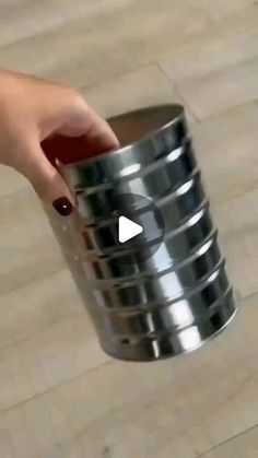 a person is holding a metal cup with their thumb on it's side, and the video appears to be playing