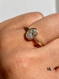 a woman's hand with a diamond ring on top of her finger, showing the center stone