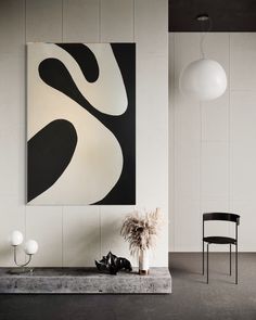 a black and white abstract painting hangs on the wall next to a table with two chairs