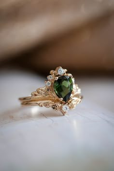 a ring with a green heart surrounded by diamonds