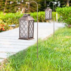 two metal lanterns are sitting on the grass