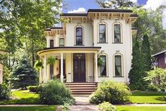 a large white house sitting in the middle of a lush green yard with lots of trees