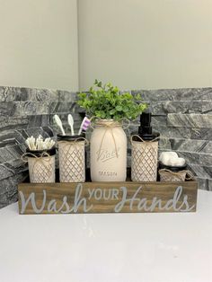 a wooden sign that says wash your hands and some bottles with toothbrushes in them