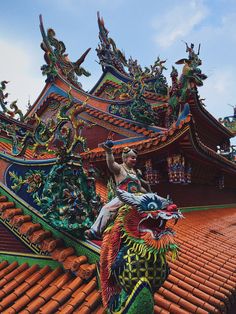 a dragon statue sitting on top of a roof next to a building with red tiles