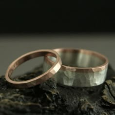 two wedding rings sitting on top of a rock