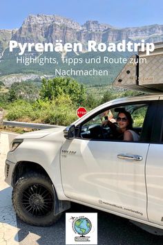 a woman sitting in the passenger seat of a white truck with mountains in the background