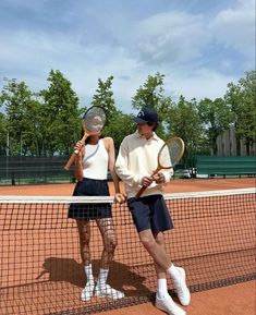 two people standing on a tennis court holding racquets