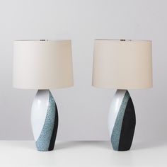 two white and black vases with lamps next to each other