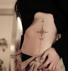 a woman's stomach with a compass tattoo on it