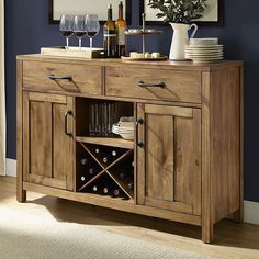 a wooden buffet table with wine glasses and plates on the top, in front of a blue wall