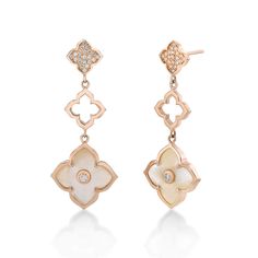 two tone gold earrings with white flowers and diamonds on each ear, set against a white background