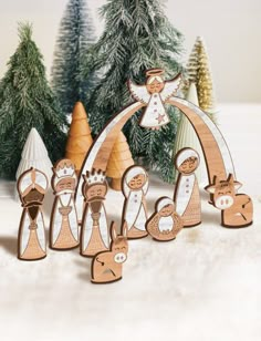 a group of wooden nativity figurines in front of christmas trees