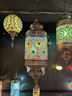 three colorful lights hanging from the ceiling in a room with other lamps on display behind them