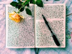 an open book with flowers and a pen on it