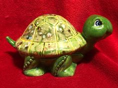 a green turtle figurine sitting on top of a red blanket