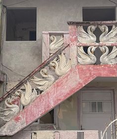 an old building with swans painted on the side and stairs leading up to it's second floor