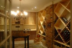 a wine cellar filled with lots of bottles next to a dining room table and chandelier