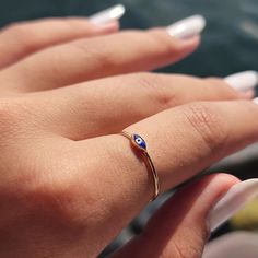 a woman's hand wearing a gold ring with an evil eye on the side