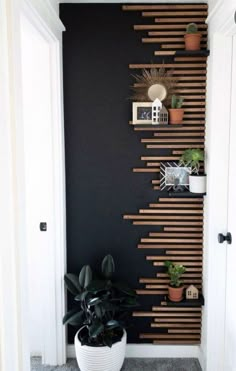 a black wall with wooden slats and potted plants on the shelf next to it