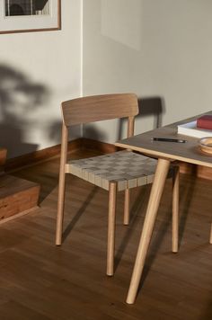 two wooden chairs sitting on top of a hard wood floor next to a table and books