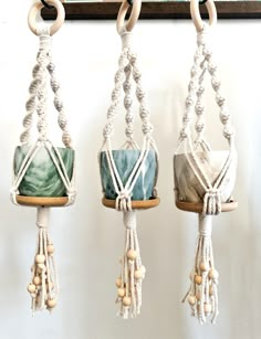 three macrame pots hanging from hooks on a wall