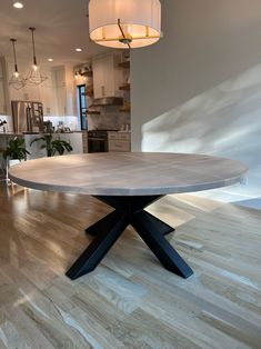 a round dining table in the middle of a room with hardwood floors and white walls