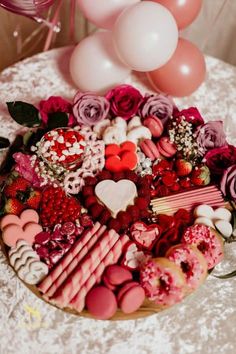 a table topped with lots of different types of food and balloons in the air above it