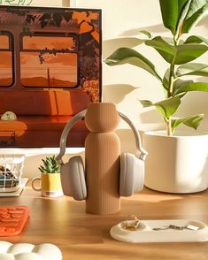 a wooden table topped with headphones next to a potted plant