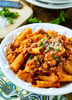 pasta with meat sauce and parmesan cheese in a white bowl on a table