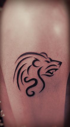 a tattoo on the leg of a woman with a lion head and snake tail in black ink