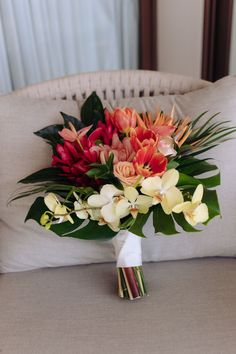 a bouquet of flowers sitting on top of a couch next to a pillow in a room