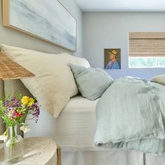 a bedroom with blue walls, white bedding and pictures on the wall above it