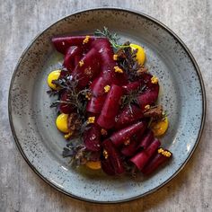 a white plate topped with beets and lemons on top of a wooden table