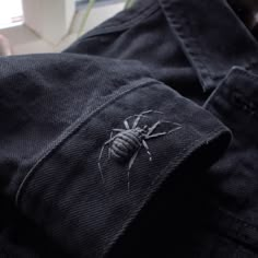 a spider is sitting on the back of a black jeant pants, which are worn by someone