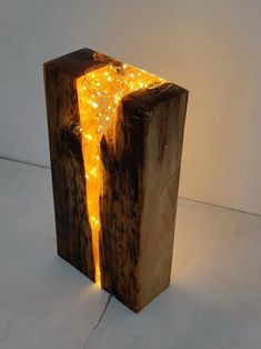 a wooden sculpture with some lights on it's sides and a white wall in the background