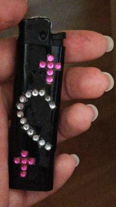 a hand holding a black case with pink and silver studded decorations on it's side