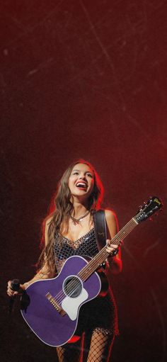 a woman holding a guitar and singing on stage